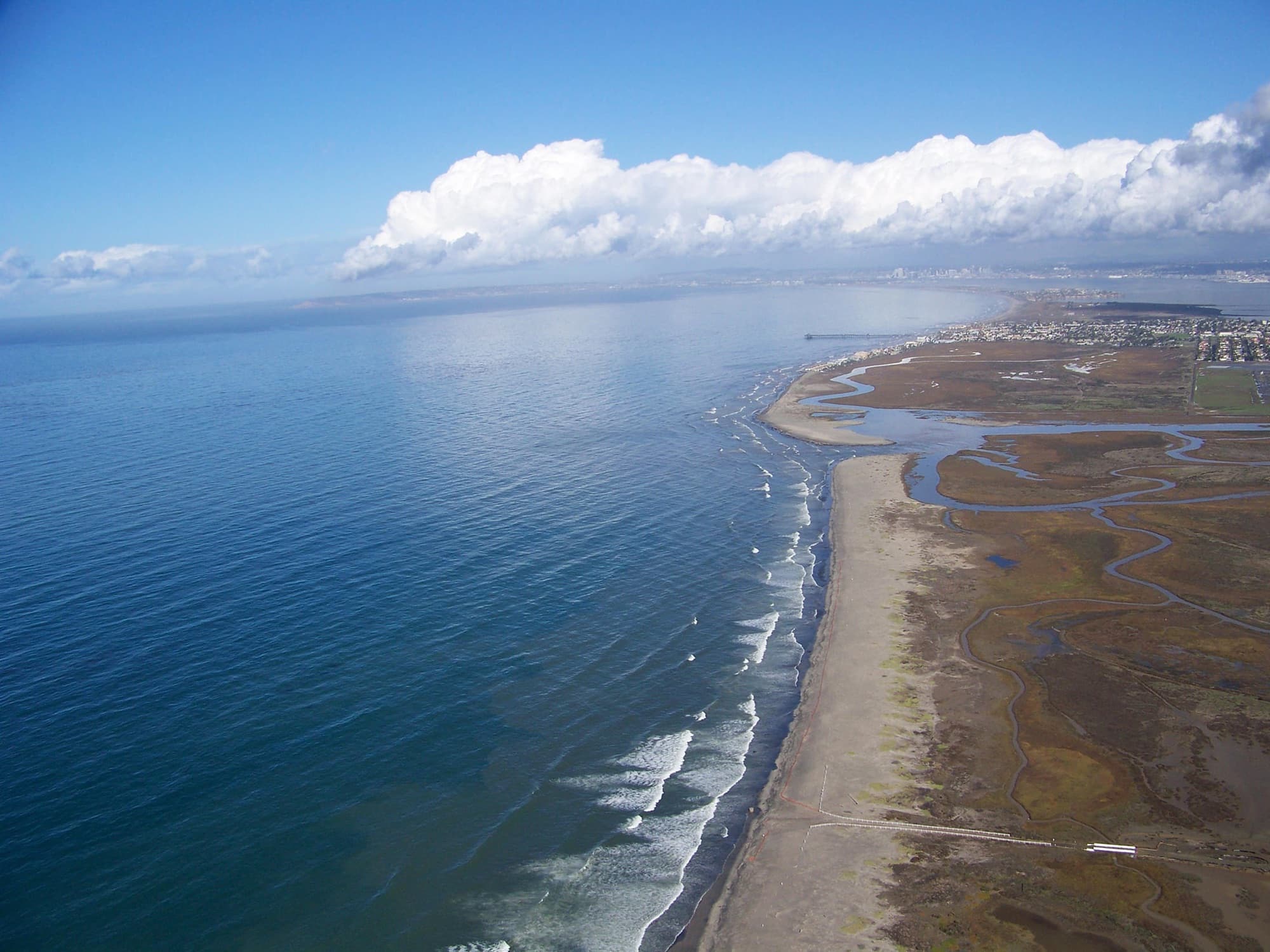 Aerial view of the Tijuana River Estuary where winding tidal channels and salt marsh meet a sandy beach and the Pacific Ocean near Imperial Beach