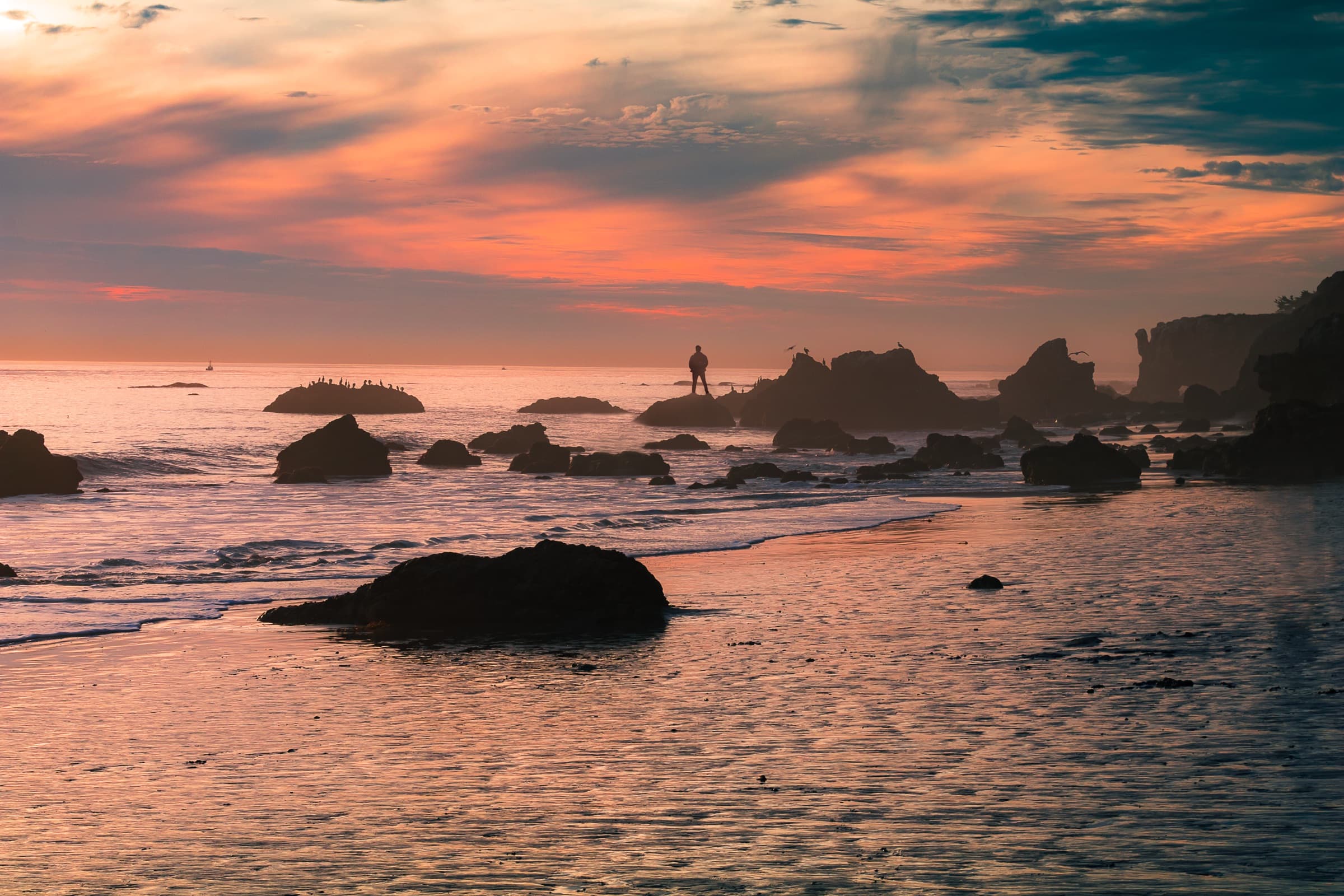 Pink and orange sunset over the sea stacks and tide pools of El Matador State Beach in Malibu, with cormorants resting on the rocks